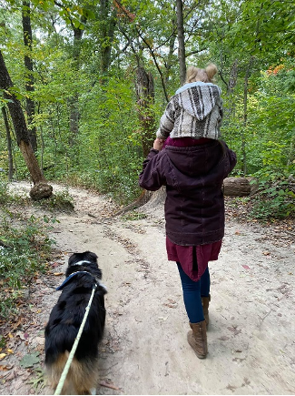 a parent and child sitting on their shoulders walking through the trails of starved rock with dog on leash