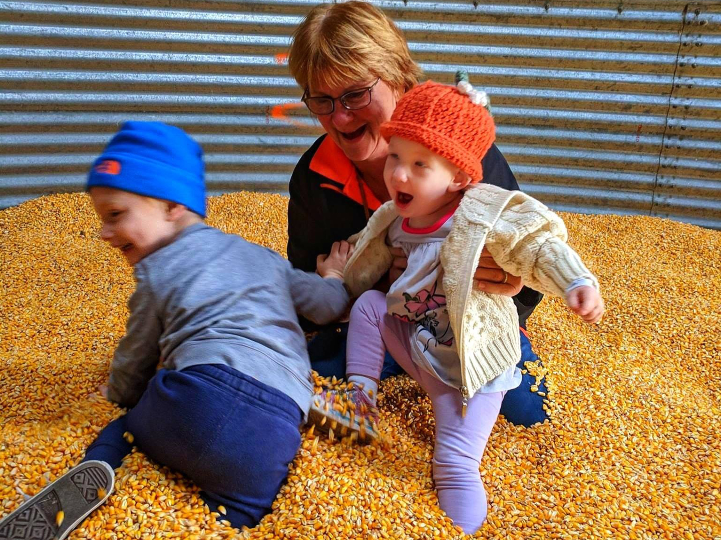 Noreen with her two grandkids playin inside the corn pit