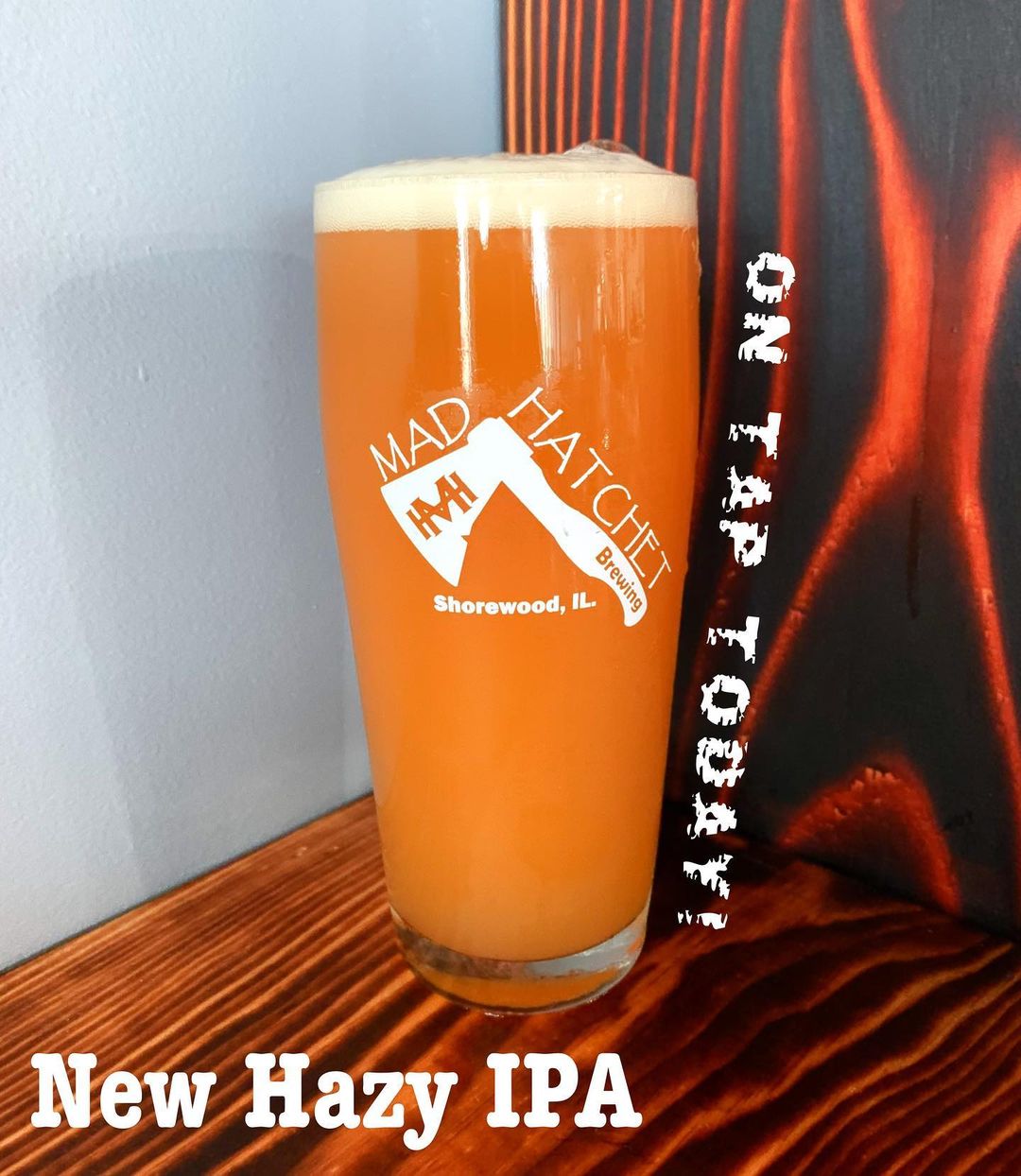 Glass of orange beer with text on tap today . new hazy ipa .. .from Mad Hatchet