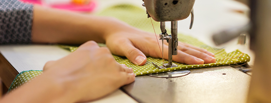 someone using a sewing machine to make a garment with green polka dot material