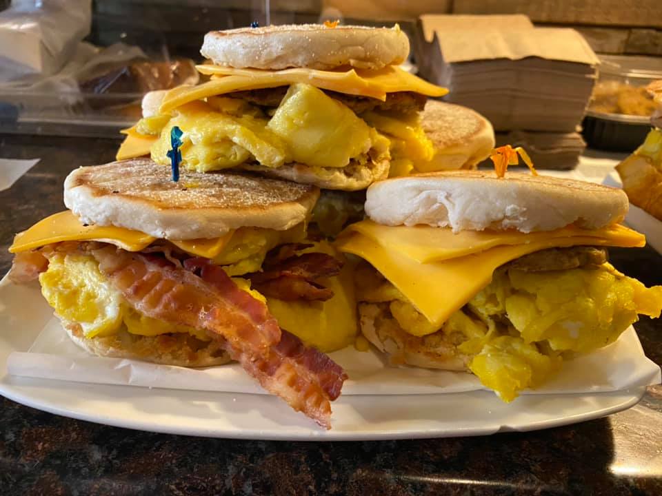 three breakfast sandwiches stacked on top each other made with eggs sausage and bacon