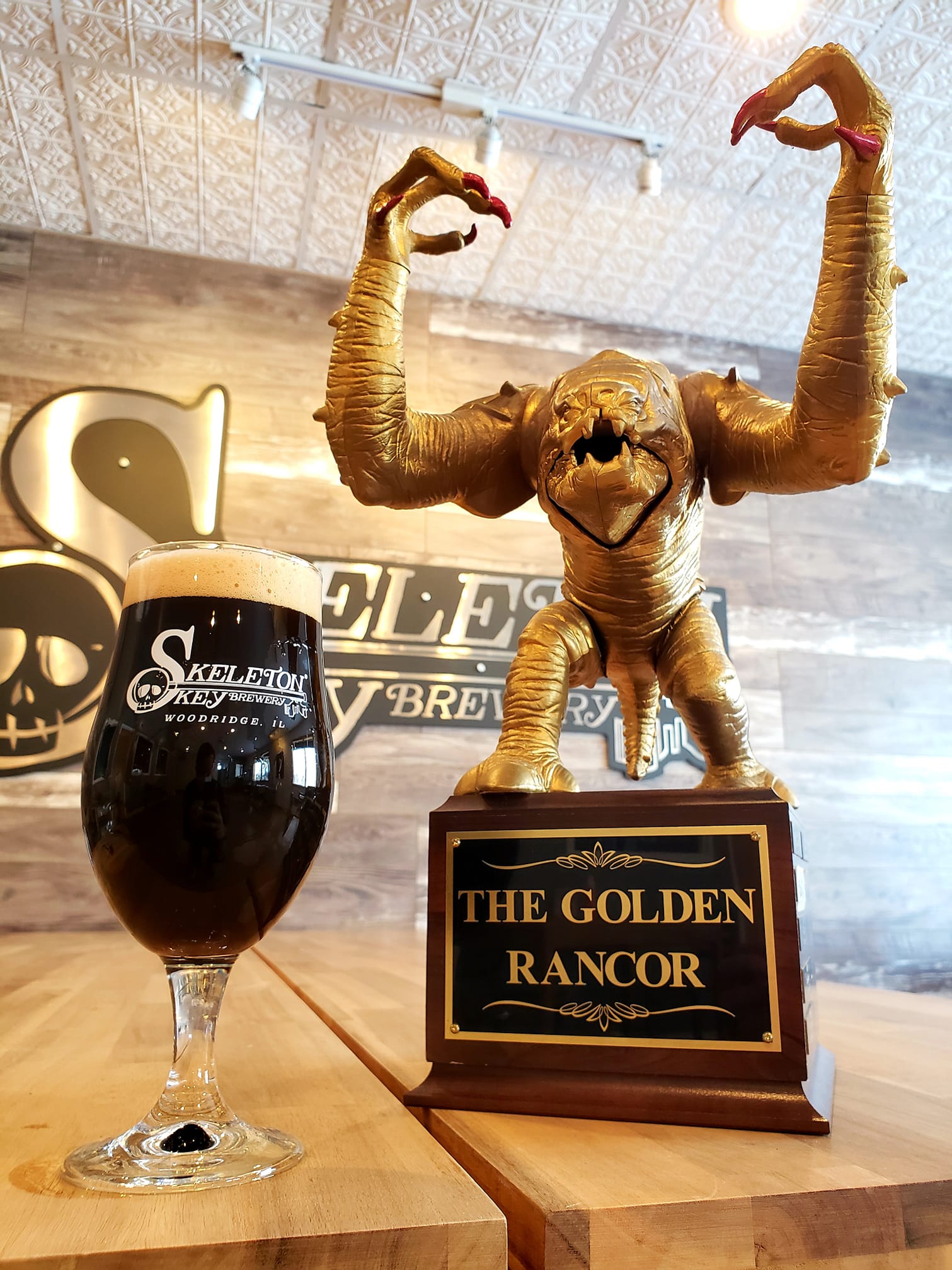 Glass of Plan for Everything from Skeleton Key Brewery next to the Golden Rancor trophy