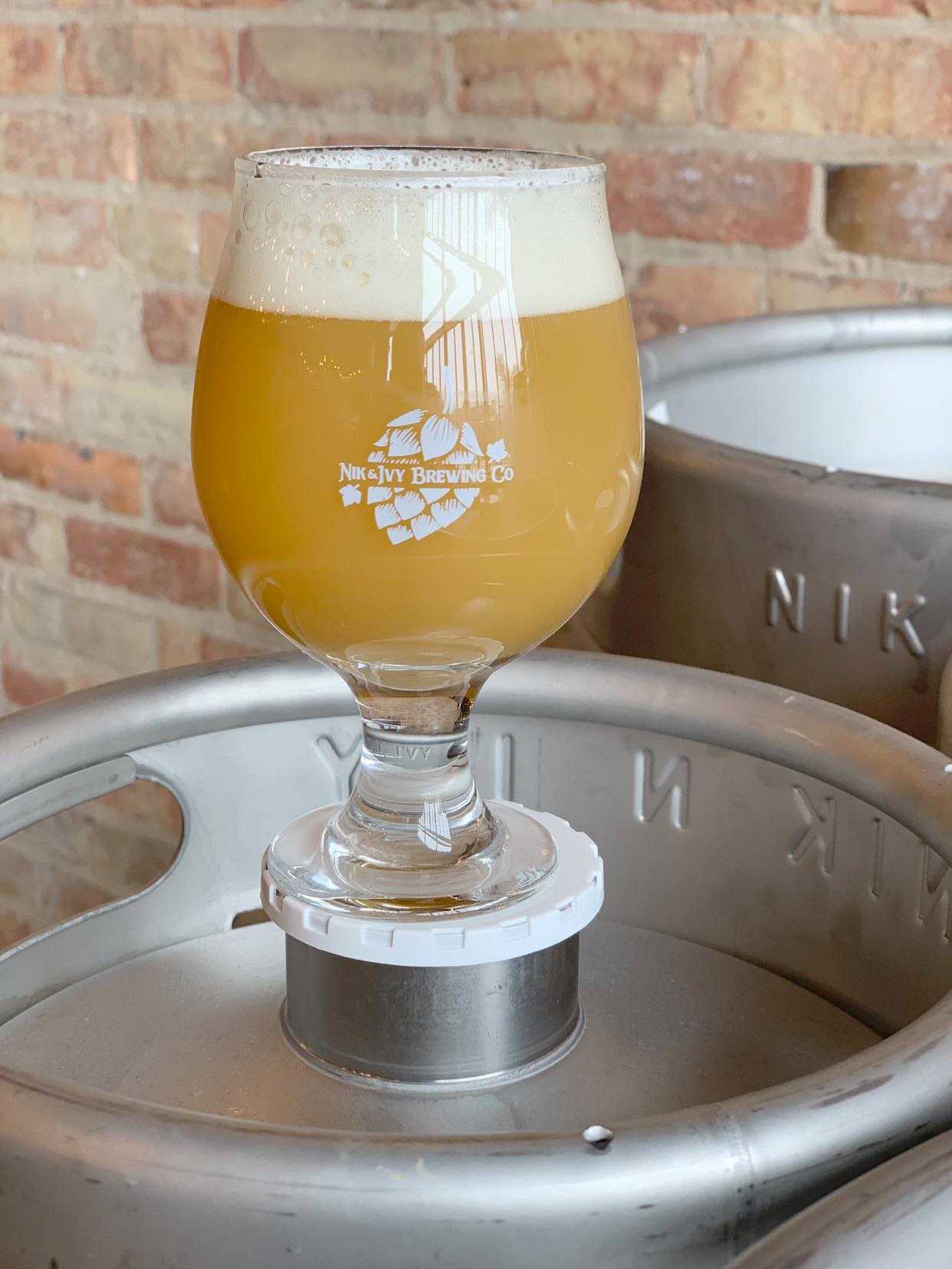 Glass of Nik & Ivy beer on top of a keg
