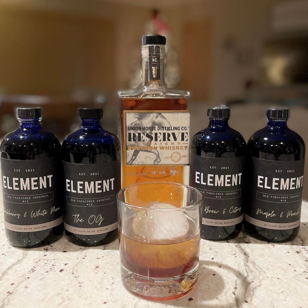 four bottle of the element with a bottle of bourbon in the middle and a glass with bourbon and ice cube 