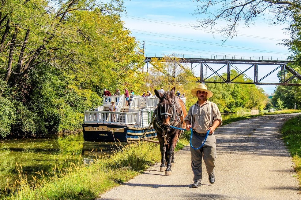 old mule pulled boat with man and horse walking on trail